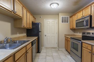 Omaha apartment for rent - A kitchen with wooden cabinets and a black refrigerator.