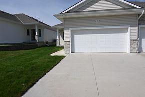 Omaha townhouse for rent - A white house with a garage door that is open.