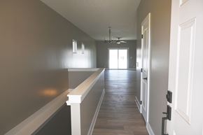 Omaha townhouse for rent - A long hallway with a white railing on the left side and a door on the right.