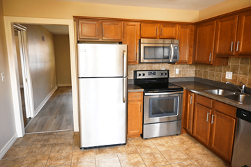 Omaha apartment for rent - A kitchen with a white refrigerator, stainless steel oven, and microwave.