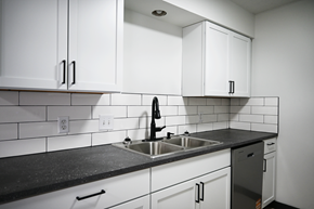 Omaha apartment for rent - A kitchen with white cabinets and a black countertop.