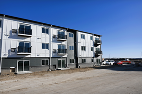 Lincoln apartment for rent - A row of white and grey apartment buildings with balconies and cars parked in the lot.