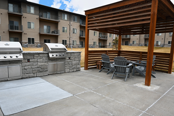 Outdoor entertainment area with televisions, lounge seating, dining tables, grilling stations and fire pit