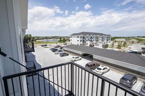 Valley apartment for rent - A balcony view of a parking lot with cars and a building in the distance.