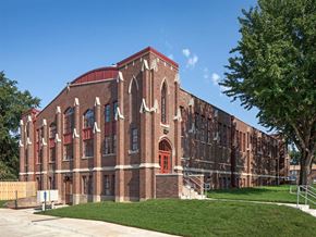 Council Bluffs apartment for rent - A large red brick building with arched windows and a red door.