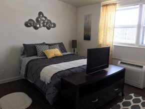 Kearney apartment for rent - A bedroom with a bed, a television, and a painting on the wall.