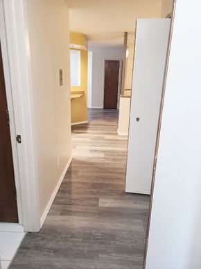 Grand Island apartment for rent - A long, narrow hallway with a white door on the left and a white cabinet on the right.