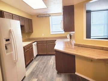 Grand Island apartment for rent - A kitchen with a white refrigerator and wooden cabinets.