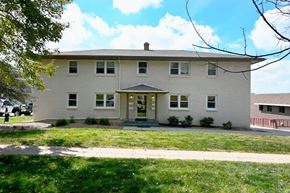 Omaha apartment for rent - A white house with a green lawn in front.