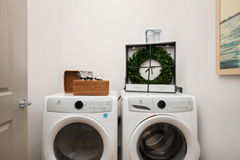 Two washing machines with a clock and a basket on top.