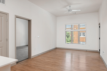 A room with a ceiling fan and a window with blinds.