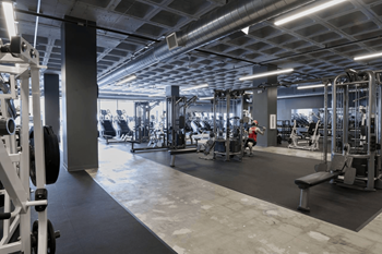 A gym with various exercise equipment and a person working out.