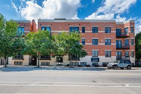 Chicago apartment for rent - A red brick building with a black car parked in front.