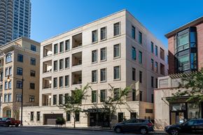 Chicago apartment for rent - A large building with a beige facade and a black car parked in front.