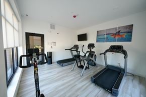 Highwood apartment for rent - a gym with various exercise equipment on the floor and a window
