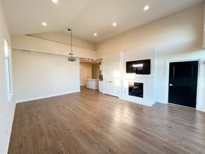Chicago apartment for rent - A spacious room with wooden flooring and a television mounted on the wall.