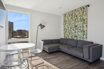 Chicago apartment for rent - A grey couch sits in a living room with a white table and chairs.