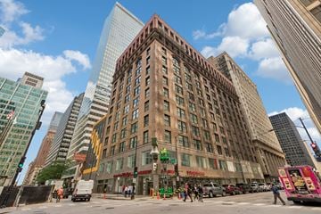Chicago apartment for rent - A city street with a large building in the middle of the frame.