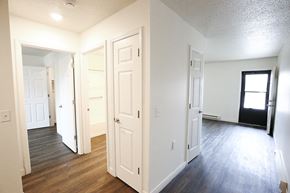 Monroeville apartment for rent - A room with white walls and wooden floors with a door open to another room.