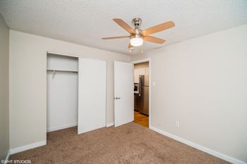 Spacious bedroom with plush carpet and ceiling fan