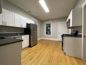 Chicago apartment for rent - A kitchen with wooden floors and black countertops.