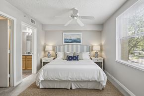 Jacksonville apartment for rent - A bedroom with a white bed and a ceiling fan.