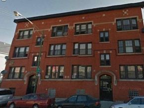 Chicago apartment for rent - A red brick building with a black door and windows.