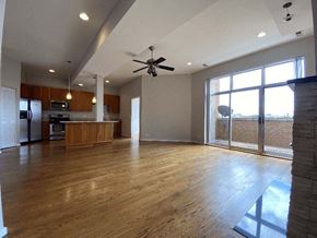 Chicago apartment for rent - an empty living room with a kitchen and a ceiling fan
