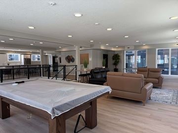 Calgary apartment for rent - A large room with a mattress on a wooden frame in the foreground and a couch and chairs in the background.
