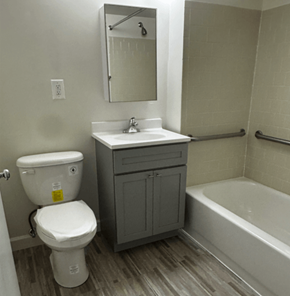 Silver Spring townhouse for rent - A white toilet with a yellow sticker on it is in a bathroom with a sink and a mirror.