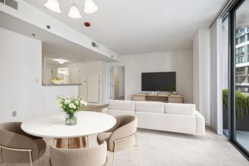 Bethesda apartment for rent - A modern living room with a white couch, a round table with chairs, and a flat-screen TV.