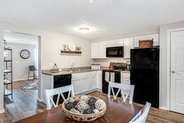 Columbus apartment for rent - A kitchen with white cabinets and a black refrigerator.