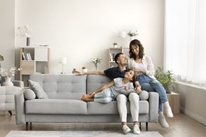 Columbus apartment for rent - A woman and a child are sitting on a grey couch with a man lying on the floor.