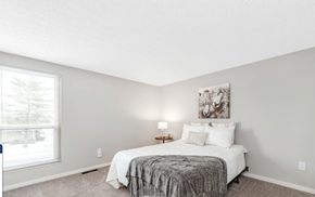 Columbus apartment for rent - A bedroom with a bed, lamp, and painting on the wall.