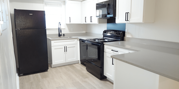 Denton apartment for rent - A black refrigerator is in a kitchen with white cabinets.