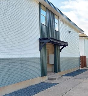 Denton apartment for rent - a white brick building with a door with a green curtain