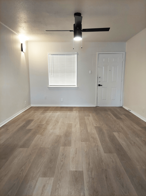 Denton apartment for rent - an empty living room with wood floors and a ceiling fan