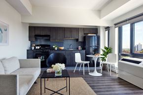 Far Rockaway apartment for rent - A modern living room with a grey sofa, a black coffee table, and a black kitchen area.