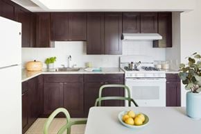 Bronx apartment for rent - A kitchen with a white fridge, white stove, and brown cabinets.