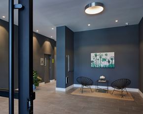 Far Rockaway apartment for rent - A hallway with a painting on the wall and two chairs with a table in front of them.