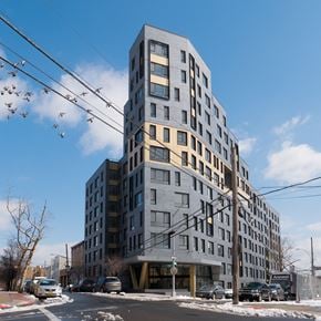 Bronx apartment for rent - A large grey building with many windows is in the foreground.