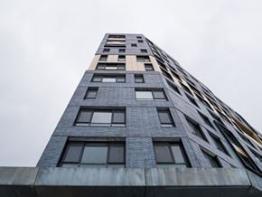 Bronx apartment for rent - A tall building with a grey facade and windows of varying sizes.