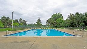 Farmington Hills apartment for rent - a swimming pool with trees and a fence around it