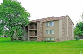 Farmington Hills apartment for rent - a building with a green lawn and a tree