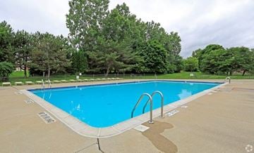 Farmington Hills apartment for rent - a blue swimming pool with trees in the background