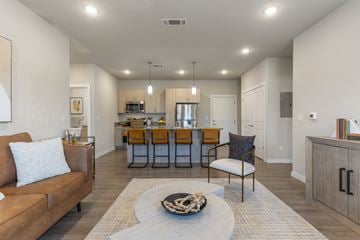 Owasso apartment for rent - A modern living room with a brown leather couch and a coffee table in the center.