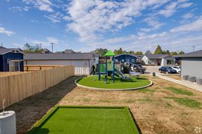 Whitestown apartment for rent - A playground with a green slide and a roundabout in the middle of a grassy area.