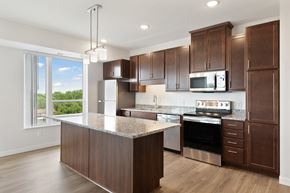 Brooklyn Center apartment for rent - A kitchen with brown cabinets and a granite countertop at Sonder Point 50+ Apartments, Minnesota