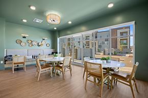 Maricopa apartment for rent - A dining room with a table set for four and a view of a building outside the window at Copa Flats Apartments, Maricopa, Arizona