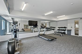 A gym with exercise equipment and mirrors in a building
